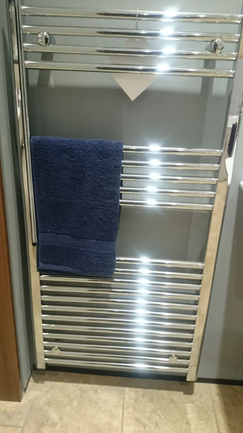 Tall chrome heated towel rail in a bathroom