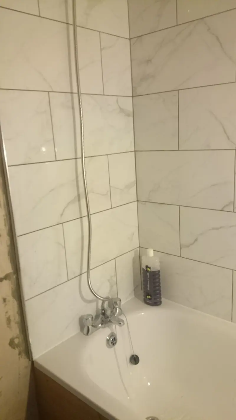 Bath with thermostatic shower mixer in a white tiled bathroom